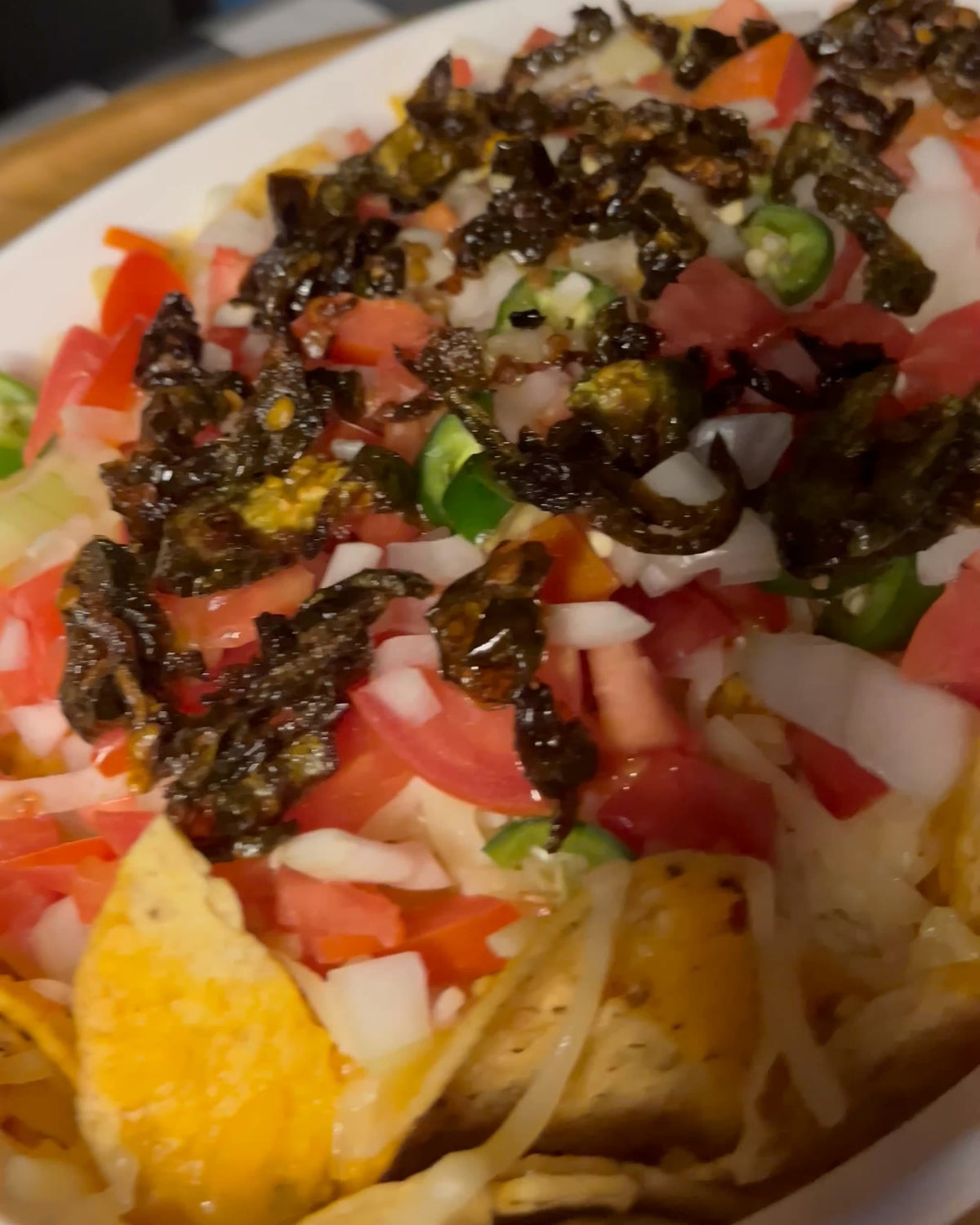 Jalapeño loaded nachos in a white baking dish, topped with salsa bandera, melted cheese and Don Chilio Spicy Jalapeño Chili Crisp