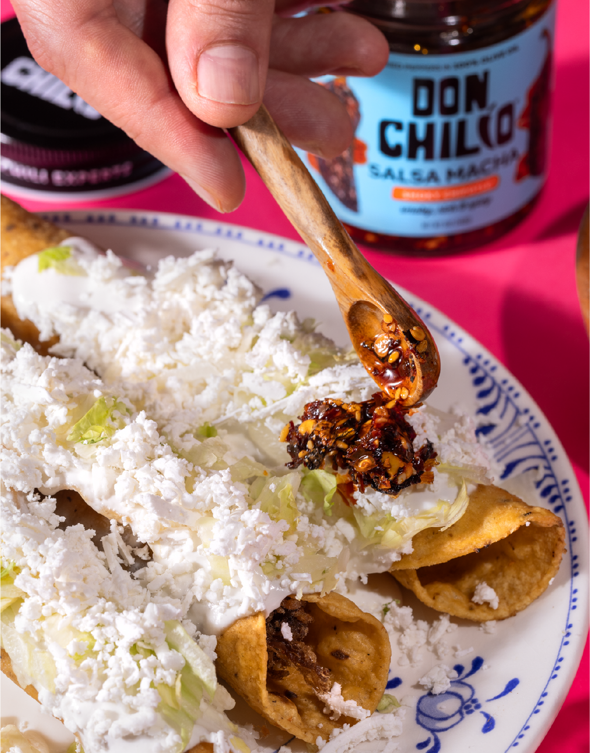 Don Chilio Smoky Chipotle Salsa Macha spooned over rolled tacos topped with crumbled queso fresco and lettuce.